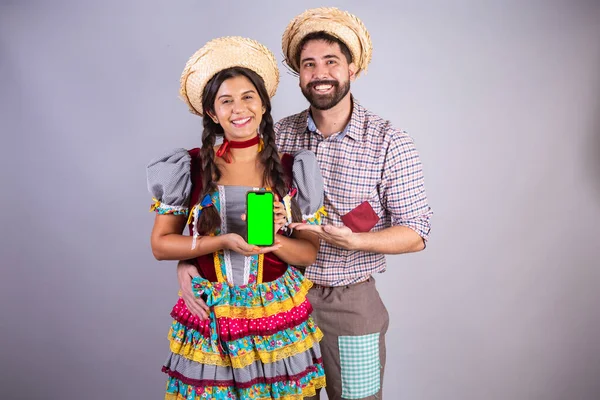 ブラジル人のカップルフェスタ ジュニナの服アラリアルフェスタ ジョー 彼氏と彼女 スマートフォンや緑の画面で — ストック写真