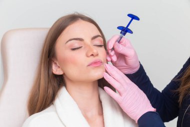 Güzellik kliniğinde bornoz giyen kadın estetik, hasta, estetik ameliyatlar. Hyaluronik asit uygulaması. Dudaklarından..