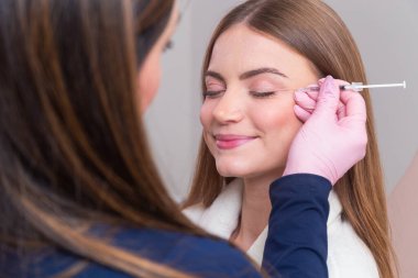 Güzellik kliniğinde bornoz giyen kadın estetik, hasta, estetik ameliyatlar. Botoks uygulaması. Kırışıklık ve yaşlanma karşıtı.