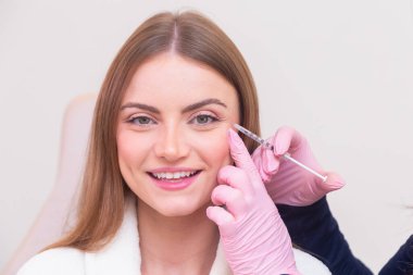 Güzellik kliniğinde bornoz giyen kadın estetik, hasta, estetik ameliyatlar. Botoks uygulaması. Kırışıklık ve yaşlanma karşıtı.