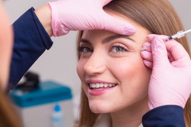 Güzellik kliniğinde bornoz giyen kadın estetik, hasta, estetik ameliyatlar. Botoks uygulaması. Kırışıklık ve yaşlanma karşıtı.