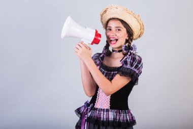 Kız, Brezilyalı, Festa Junina, Arraial, Festa de So Joao kıyafetleriyle. Yatay portre. Megafonla, reklam promosyonuyla.
