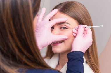 Güzellik kliniğinde bornoz giyen kadın estetik, hasta, estetik ameliyatlar. Botoks uygulaması. Kırışıklık ve yaşlanma karşıtı.