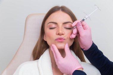 Güzellik kliniğinde bornoz giyen kadın estetik, hasta, estetik ameliyatlar. Hyaluronik asit uygulaması. Dudaklarından..