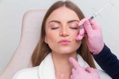 Güzellik kliniğinde bornoz giyen kadın estetik, hasta, estetik ameliyatlar. Hyaluronik asit uygulaması. Dudaklarından..