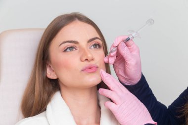 Güzellik kliniğinde bornoz giyen kadın estetik, hasta, estetik ameliyatlar. Hyaluronik asit uygulaması. Dudaklarından..