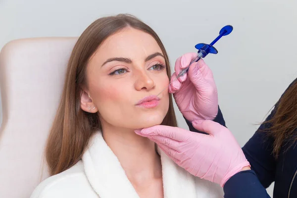 Güzellik kliniğinde bornoz giyen kadın estetik, hasta, estetik ameliyatlar. Hyaluronik asit uygulaması. Dudaklarından..