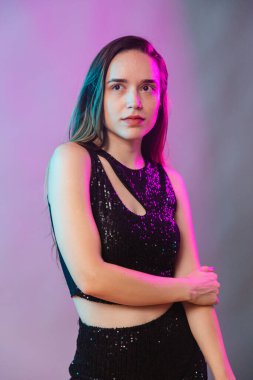 Mavi ve pembe neon arka planda, fotoğraf için poz veren, aydınlatılmış bir model. dikey resim.