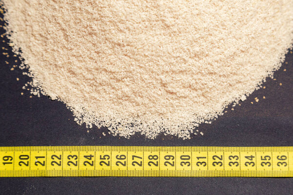 пшеница, куча пшеничных отруби рядом с измерительной лентой, черный фон, генерируемый с экструдером машины