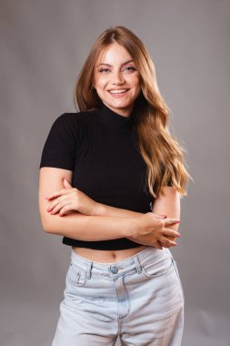 Güzel sarışın, siyah gömlek giyen Brezilyalı kadın. Dikey portre, model, kollarını kavuşturarak gülümsüyor..