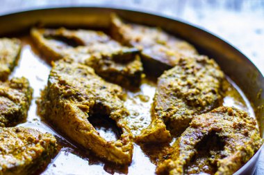 Sorshe ilish or hilsa fish curry cooked with mustard seeds served on a plate. Pieces of fish are seen in rich yellow gravy. This is very popular traditional delicacy in Bengali culture. clipart