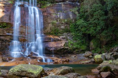 Meghalaya 'nın kayalık tepelerinden akan Wei sohphoh şelalesi. Canlı yeşil lagün suyu olan beyaz derelerin uzun pozlama fotoğrafı.
