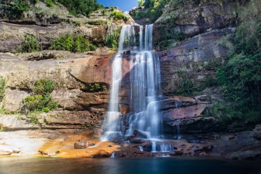 Meghalaya 'nın kayalık tepelerinden akan Wei sohphoh şelalesi. Canlı yeşil lagün suyu olan beyaz derelerin uzun pozlama fotoğrafı.