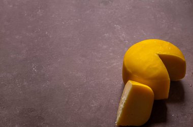 Gouda peyniri çarkı kırmızı arka planda dilimlenmiş. Geleneksel Hollanda peyniri.