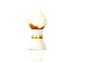 Chicken egg on a stand is peeled on a white background. Seamless video loop