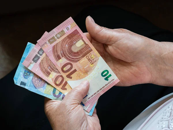Elinde küçük Euro banknotları tutan yaşlı bir kadının elleri. Yukarıdan görüntüle