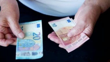 Küçük euro banknotları sayan yaşlı bir kadının elleri