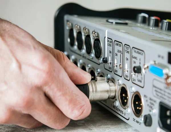 stock image A man's hand connecting an XLR female cable to the output of a mixing console