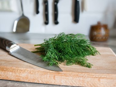 Bir demet taze dereotu ve kayın kesme tahtasının üzerinde bir bıçak.