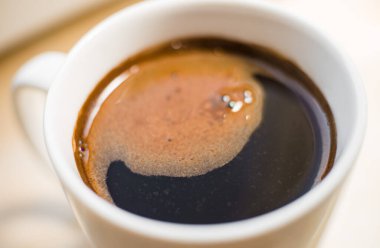 White mug of fresh coffee with appetizing tiger-colored foam close-up
