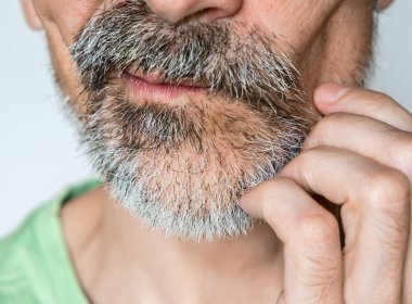 Orta yaşlı bir adam nazikçe tıraşsız yüzünü kaşıyordu.