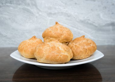 Taze pişmiş altın profiterol tabakta. Kremalı pasta..
