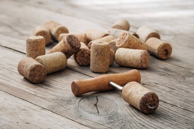 Şarap mantarları ve tirbuşon eski ahşap boyanmamış masada.