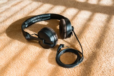 Pofuduk bir ekosenin üstündeki kulaklıklar perdelerin ardında. Arkaplan