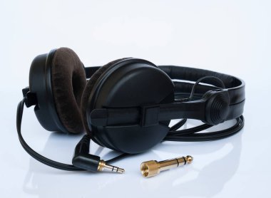 Profesyonel DJ siyah kulaklıklı, kadife kulaklıklı ve altın kaplamalı, beyaz arka planda yansıması olan 6.3 mm kriko adaptörlü..