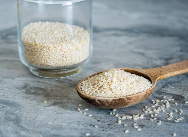 Cam kavanoz ve susam tohumlarıyla dolu tahta kaşık.