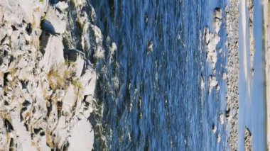 Suda kayalık kıyıları ve kayaları olan geniş bir nehrin hızlı akışı. Dikey video