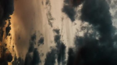 Gün batımındaki zaman atlaması sırasında gökyüzünde hareketsiz, karamsar kara bulutların hareketleri. Dikey video