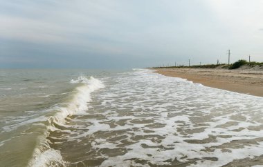 Akşamları ufka uzanan kumlu bir sahilde deniz sörfü.