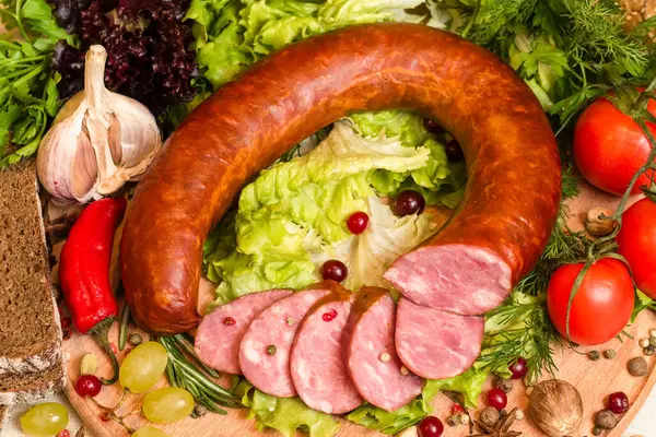 Domatesli, dereotlu, marullu, üzümlü, baharatlı, sarımsaklı, acı biberli ve tahta kesme tahtasındaki ekmek parçalı ev yapımı füme sosis.