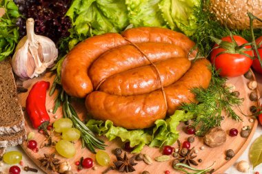 Ev yapımı tütsülenmiş sosis kesme tahtasına bağlanmış baharatlar, domatesler, sarımsak ve diğer sebzelerle birlikte.