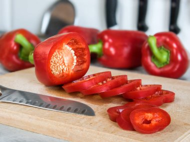 Santoku bıçağı ve kırmızı biber (kırmızı biber, kırmızı biber) kayın ağacı kesme tahtasının üzerinde.