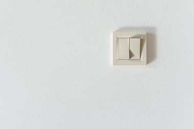 Beyaz bir duvardaki elektrik düğmesinin ön görüntüsü.