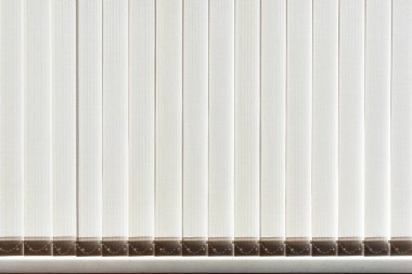 Penceredeki dikey kumaş jaluzileri güneş ışığıyla aydınlatılıyor. Arkaplan