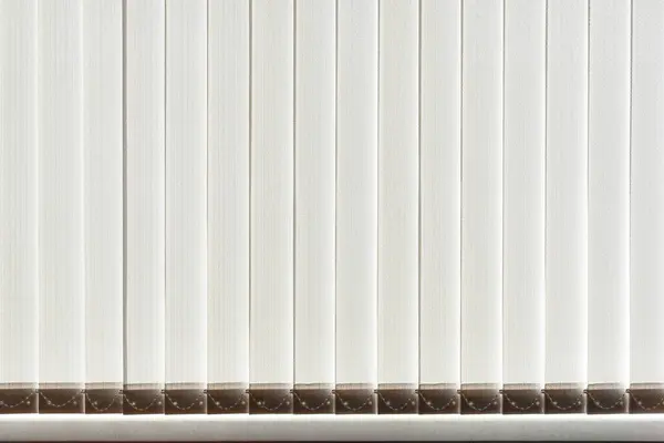 Penceredeki dikey kumaş jaluzileri güneş ışığıyla aydınlatılıyor. Arkaplan