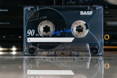 Zaporizhzhia, Ukraine - December 24, 2023: BASF CE II Chrome Extra 90 audio cassette in front of cassette deck with reflection clipart