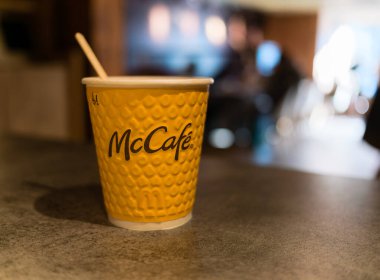 Lviv, Ukrayna - 25 Mart 2024: Sarı kağıt McKafe kahve fincanı ile McDonald 's restoranının taş tezgahında karıştırma çubuğu ile sabah güneşinin altında