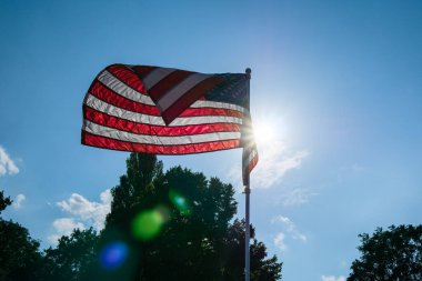 ABD bayrağı rüzgarda dalgalanıyor. Güneş ışınlarının ışığında. Mercek Fişeği