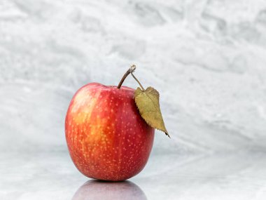 Gri mermer yüzeyinde yaprak bulunan kırmızı elma (gala çeşidi). Arkaplan