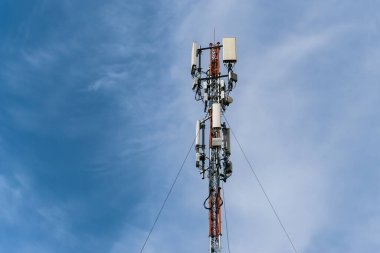 Mavi gökyüzüne karşı iki katmanlı hareketli hücresel antenli uzun bir direğin tepesi.