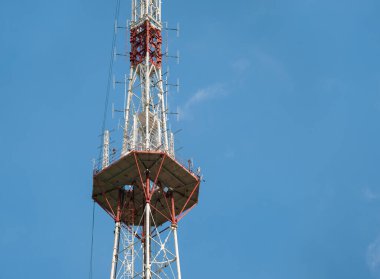 Mavi gökyüzüne karşı yüksek metal bir televizyon yayın kulesinin üst katlarından biri.