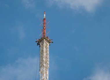 Mavi gökyüzüne karşı yüksek bir metal televizyon yayın kulesinin tepesinde. Arkaplan