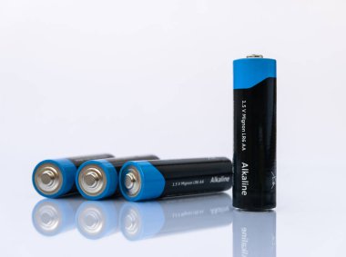 Dört adet Alkline 1.5V Mignon LR6 AA bataryası beyaz zemin üzerinde yansıma ile izole edildi.