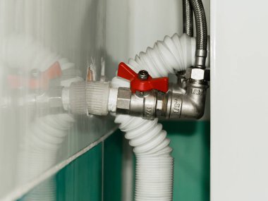 Lavabonun altında esnek hortumları ve plastik boruları olan yarım inçlik bir su topu vanası..