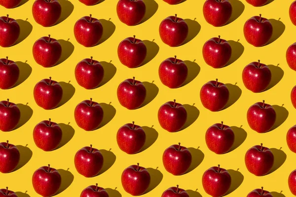 薄黄色の背景に赤いリンゴで作られたトレンディなフルーツパターン ミニマルなコンセプト — ストック写真