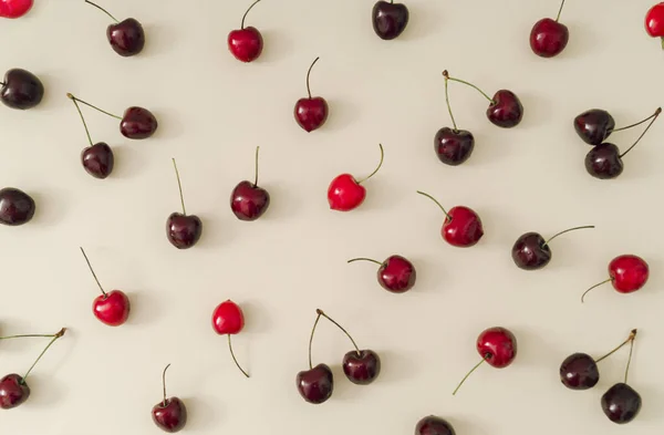 stock image Trendy fruit pattern made of red cherries on light pastel cream background. Minimal cherry fruit layout. Creative nature summer pattern concept. Flat lay summer food idea.